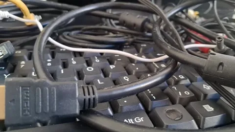 Tangled computer cables on a keyboard. Messy electronic wires and hardware Stock Footage 340241512