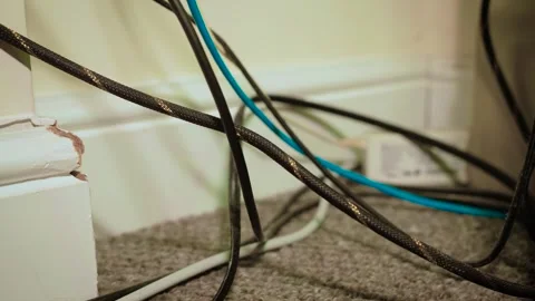 Tangled computer wires running along baseboard behind desktop setup. Network Stock Footage 340326602