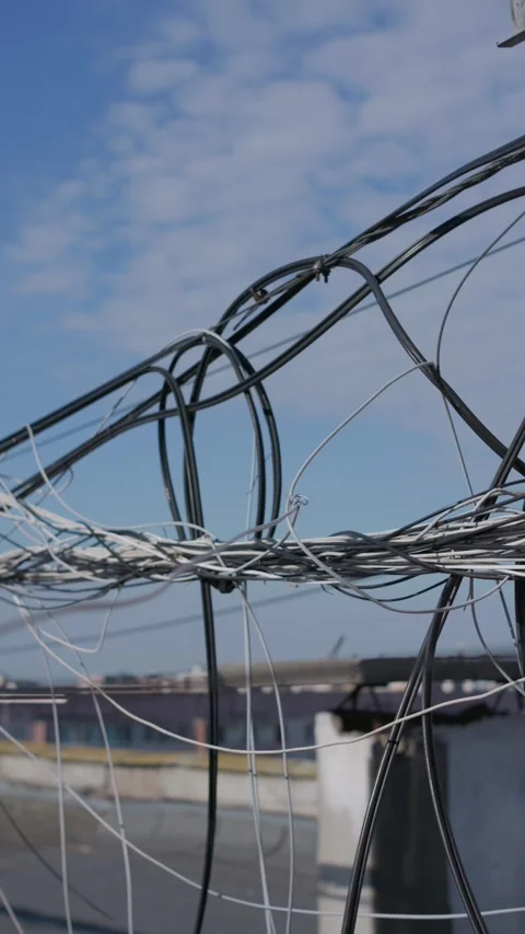 Tangled Data Cables Hanging from a Rooftop Structure in Daylight Close-Up Stock Footage 347542963