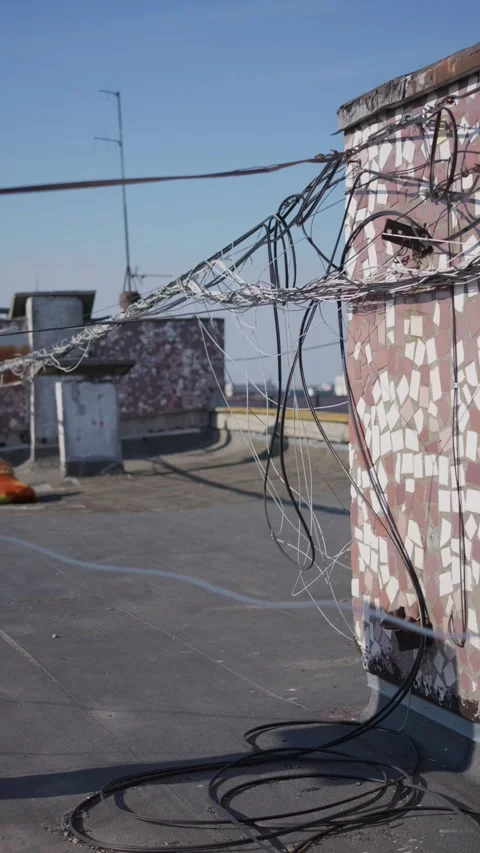 Tangled Internet Data Cables Stretching Across Rooftop Wall in Daylight Видео 347545132