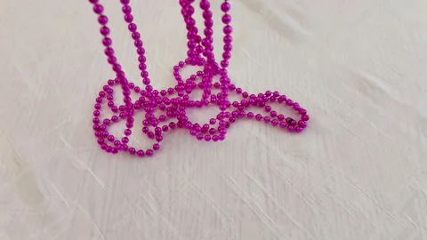 Tangled Metallic Pink Beads on Soft Textured Surface Closeup Scene Video stock 327587111