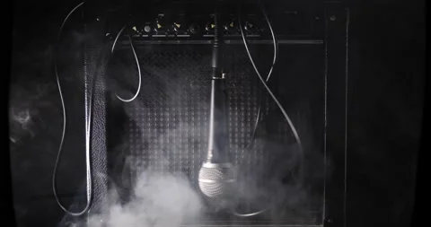 Tangled microphone and wires swinging in front of guitar amplifier isolated  Video stock 204960067