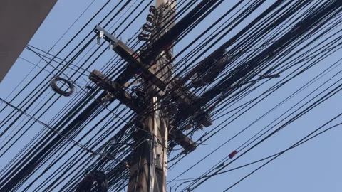 Tangled power lines and electric cables on utility pole against blue sky in Stock Footage 332065225