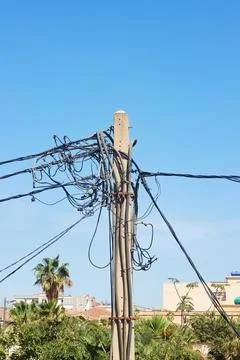 Tangled Power Lines on a Concrete Utility Pole Against Clear Blue Sky in Urban N Stock Photos