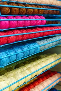 Tangles of multi-colored threads and yarn in rows on metal stand. Stock Photos