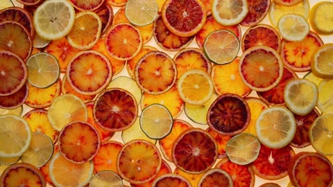 Tangy Citrus Splash: Fruit Background with Oranges, Lemons, and Limes Cut into Stock Footage 241325103