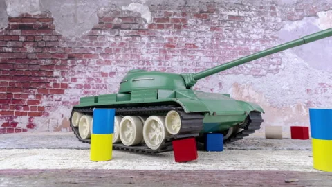 Tank facing forward, between Ukainian and Russian color flags. Damaged brick Video stock 213222775