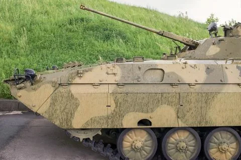 Tank with a raised muzzle against the background of green grass close-up Stock Photos