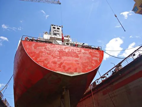 Tanker in dry dock is being cleaned and painted on outer hull of the vessel.. Stock Photos