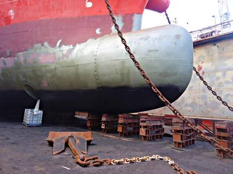 Tanker in dry dock is being cleaned and painted on outer hull of the vessel.. Stock Photos