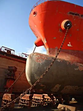 Tanker in dry dock is being cleaned and painted on outer hull of the vessel.. Stock Photos