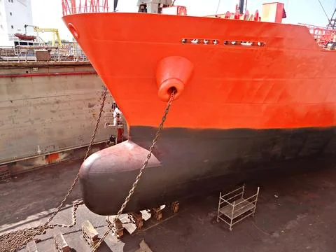Tanker in dry dock is being cleaned and painted on outer hull of the vessel.. Stock Photos