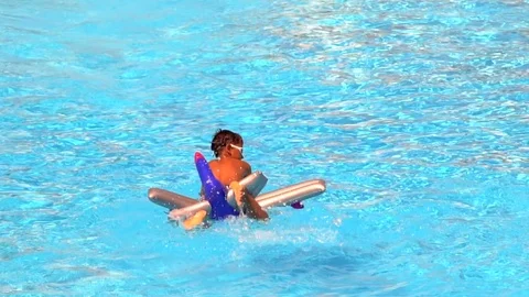 Tanned boy silhouette on inflatable float toy in blue water of swimming pool Stock Footage 88538234