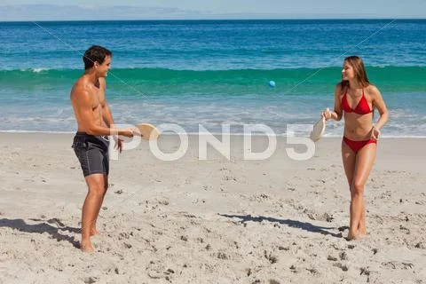 Tanned couple playing with beach racket Stock Photos