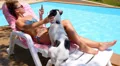 Tanned Woman Using Smart Phone by the Poolside with a Dog. Caucasian Female HD Footage