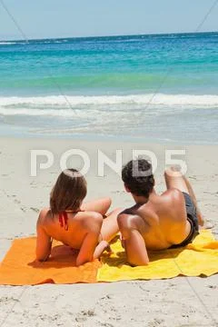 Tanned young lovers lying on the beach Stock Photos