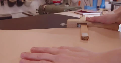Tanner cuts an even strip from a sheet of leather with a special knife. Stock-Footage 150319232