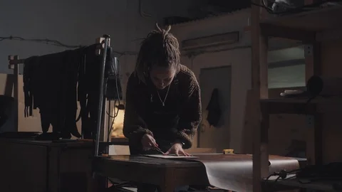 Tanner with dreadlocks works in an art studio makes a leather product. Vídeo Stock 124520111
