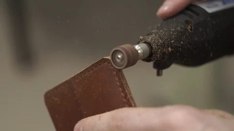 The tanner, with the help of Dremel, polishes the edges of leather goods. Close Stock Footage 104927110