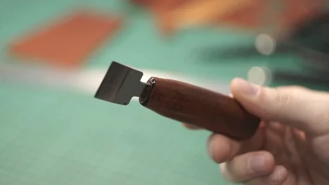 The tanner holds in hands a flat knife for work with skin. Handmade tool. Wooden Stock Footage 104926644