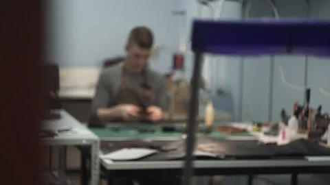 Tanner manually stitches a leather product. Man sews a brown leather wallet Stock Footage 104927284