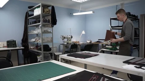 Tanner manually stitches a leather product. Man sews a brown leather wallet Stock Footage 104927344