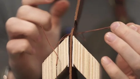 Tanner manually stitches a leather product. Man sews a brown leather wallet Stock Footage 104927608