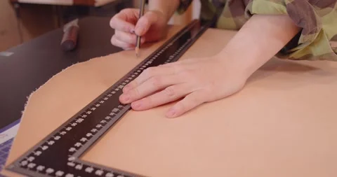 A tanner measures a large sheet of leather with a ruler for making a bag Stock Footage 148390922
