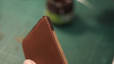 Tanner paints the paint ends of the wallet. Brown paint for painting leather. Stock Footage 104926929