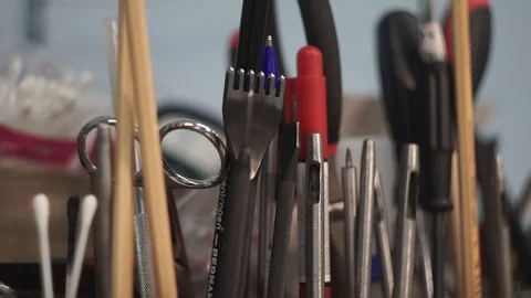 The tanner picks up a punch for working with leather. Many different tools for Stock Footage 104927648