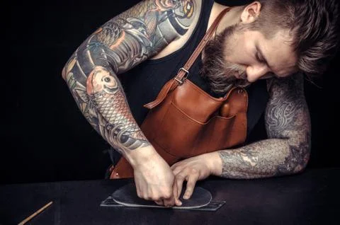 Tanner processing a leather workpiece at leather studio Foto stock