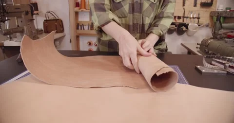 The tanner rolls up a large sheet of leather Vídeos de archivo 150126459