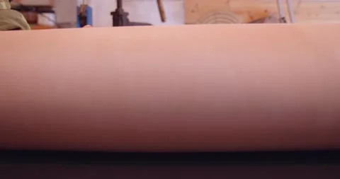 Tanner rolls out a sheet of leather on the table. big roll of leather Stock Footage 148390808