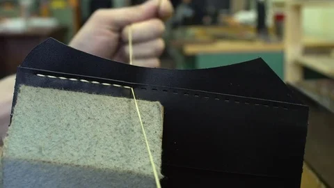 The tanner sews the leather workpieces. Handmade in a small manufactory close-up Stock Footage 77879680