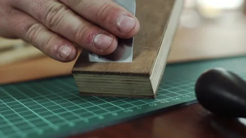 A Tanner sharpens a stencil knife on a leather sharpener. The traditional Stock Footage 133569430