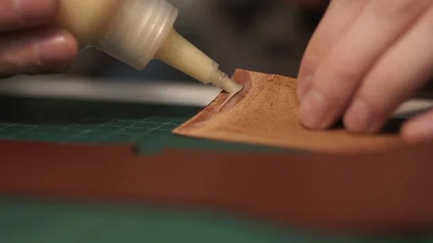 Tanner squeezes the glue out of the bottle. Sticks pocket to leather wallet Stock Footage 104925880