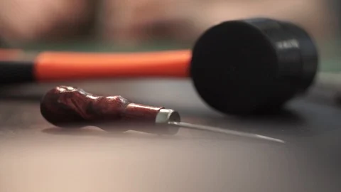 The tanner takes a rubber mallet with a red handle from the table. On the table Stock Footage 104927653