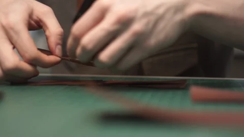 Tanner works in the workshop. Sitting at the table glues a purse of parts. Works Stock Footage 104925502