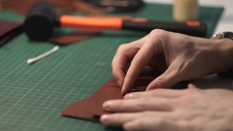 Tanner works in the workshop. Sitting at the table glues a purse of parts. Works Stock Footage 104925503