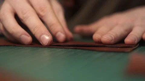 Tanner works in the workshop. Sitting at the table glues a purse of parts. Works Stock Footage 104925602