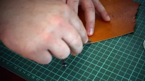 The Tanner's hands draw a line on the edge of the fabric with a marking divider Stock Footage 134601684
