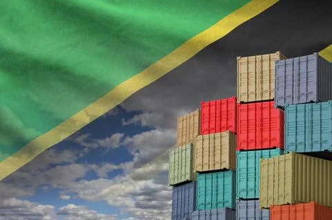 Tanzania flag and big stack of shipping cargo containers in docks with sky Foto stock