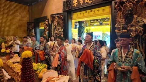 Taoist priest are in front of a table with fruit and flowers Видео 318095955