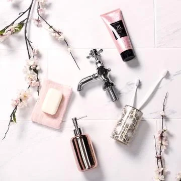 A tap, a jar of soap, a solid soap, toothbrushes and some brunches of pink fl 스톡 사진