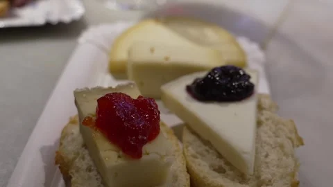 Tapas platter with assorted cheeses on artisanal bread, topped with red and 스톡 동영상 336757578