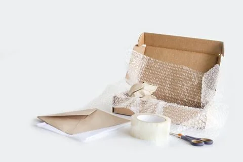 Tape, box, bubble wrap, scissors, paper envelope. Product packaging concept. Stock Photos