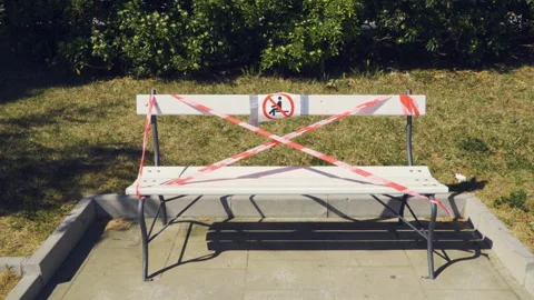 Tape with Closed Park No Access sign tied around a park bench Stock Footage 131118489