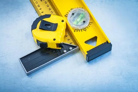 Tape line construction level and square ruler on metallic background 스톡 사진