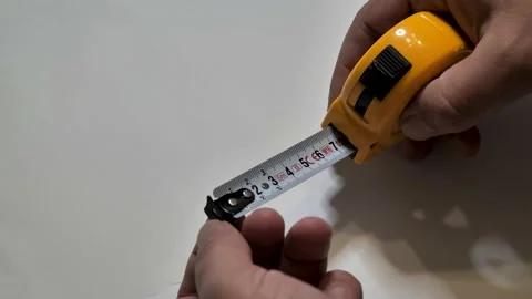 Tape measure. Hands pull the measuring yellow tape out. Roll of measuring Stock Footage 162329491