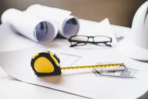 Tape measure is placed on the work table with a house plan designed Including Stock Photos